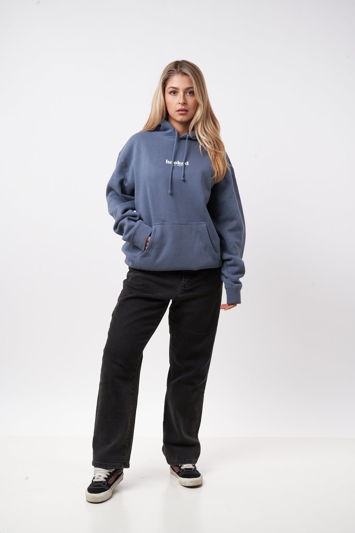 Person wearing a blue hoodie and black pants on a white background