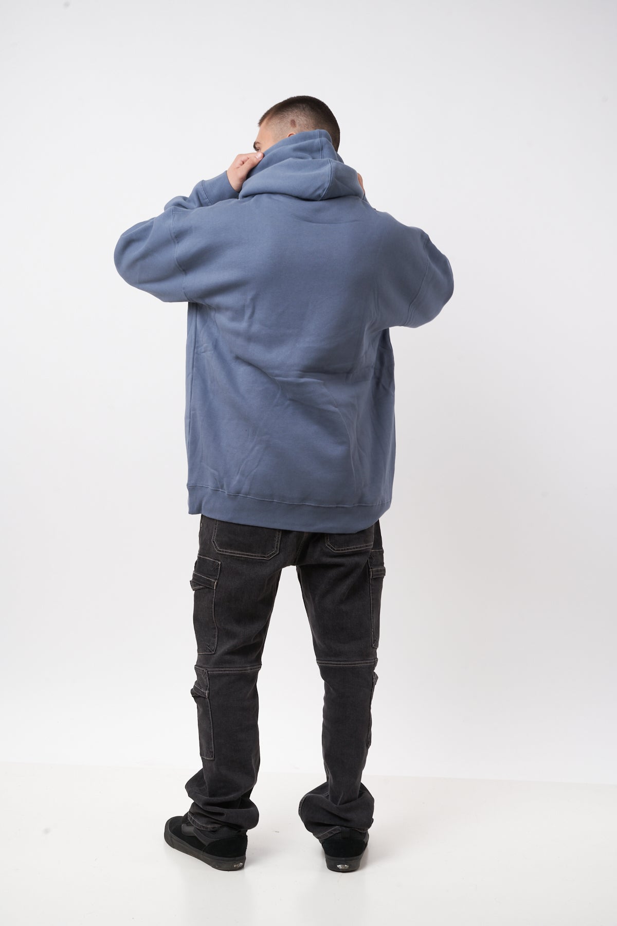 Person wearing a blue hoodie and black pants on a white background