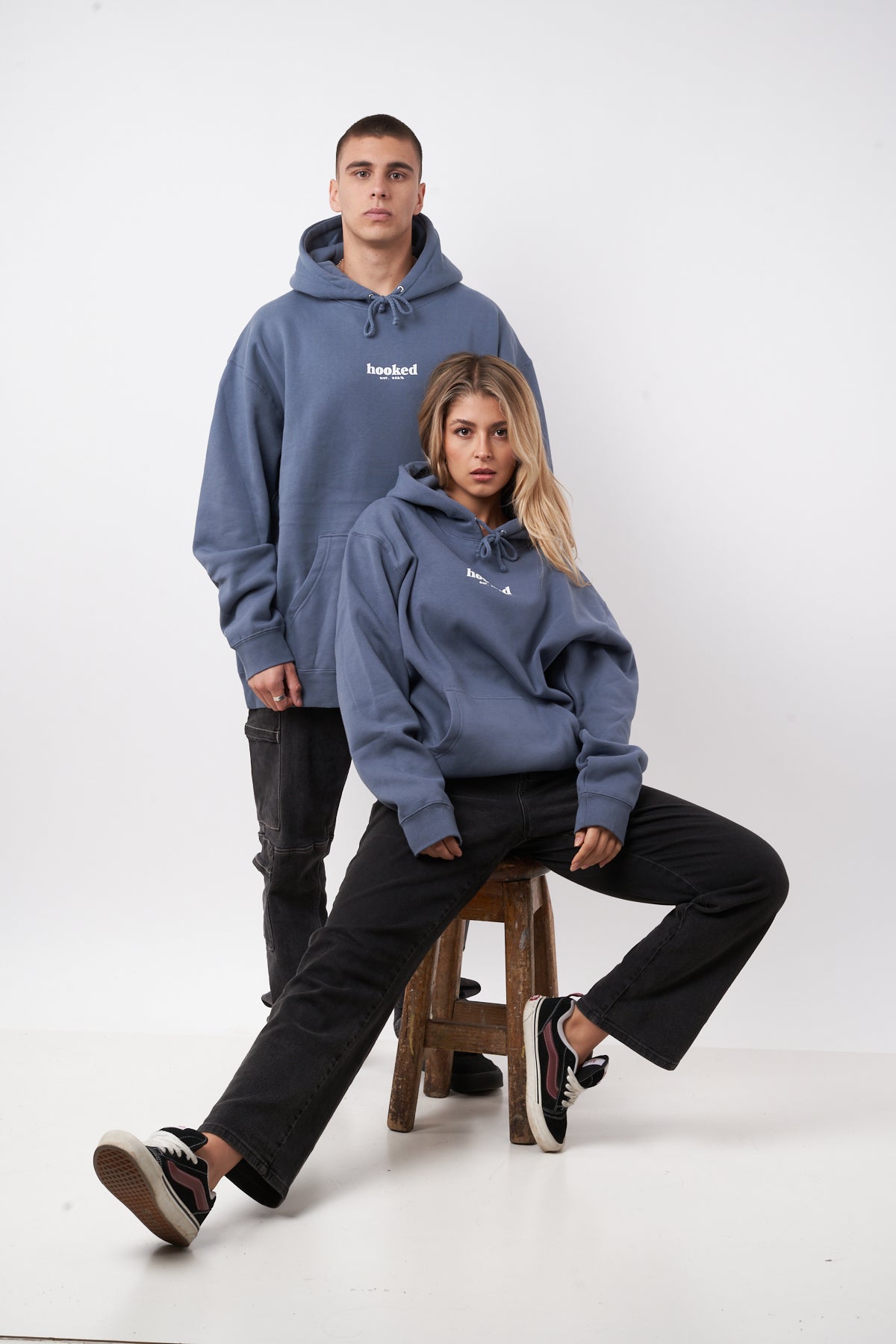 Two people wearing blue hoodies with a brand logo on a white background