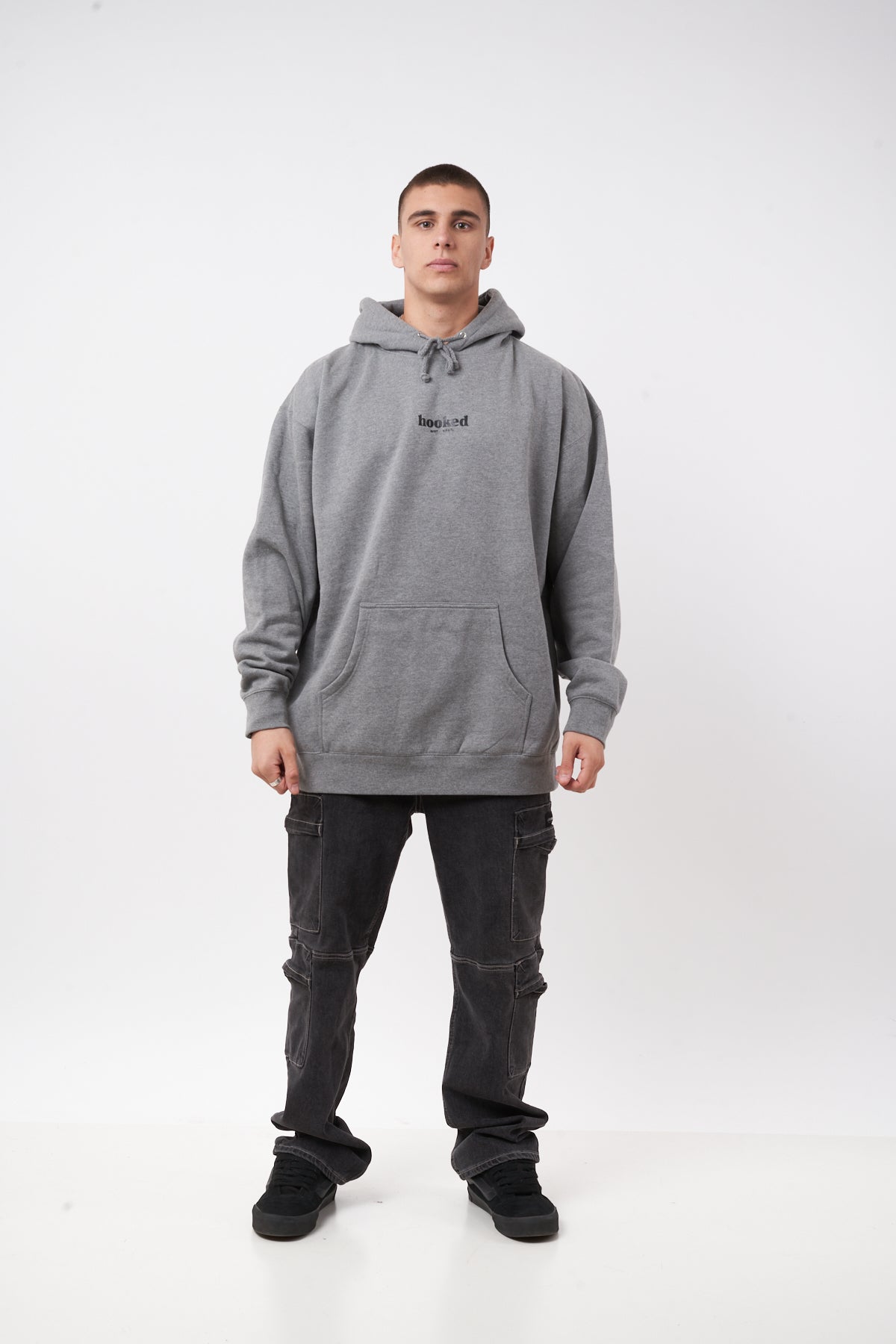 Person wearing a gray hoodie and dark pants on a white background