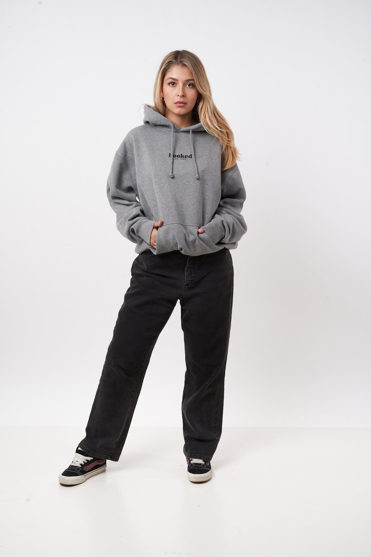Person wearing a gray hoodie and black pants on a white background