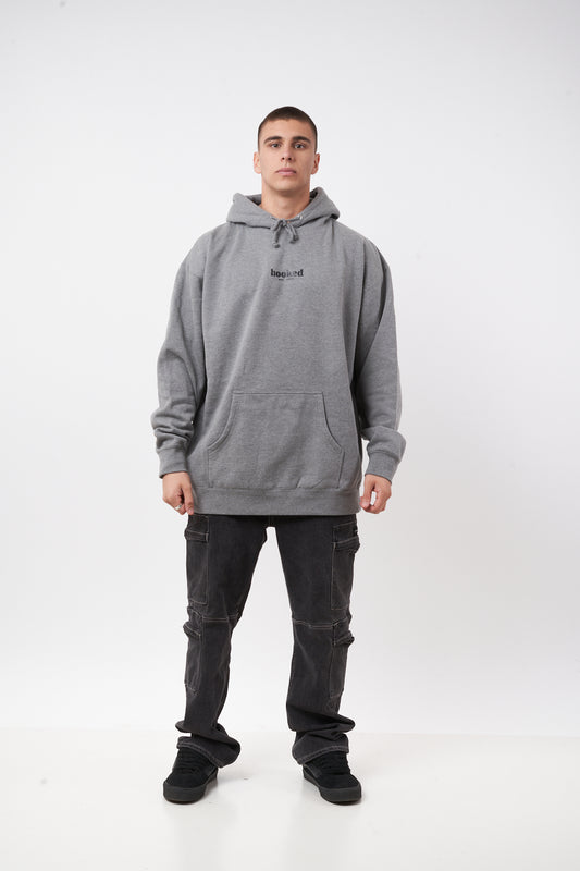 Person wearing a gray hoodie and dark pants on a white background